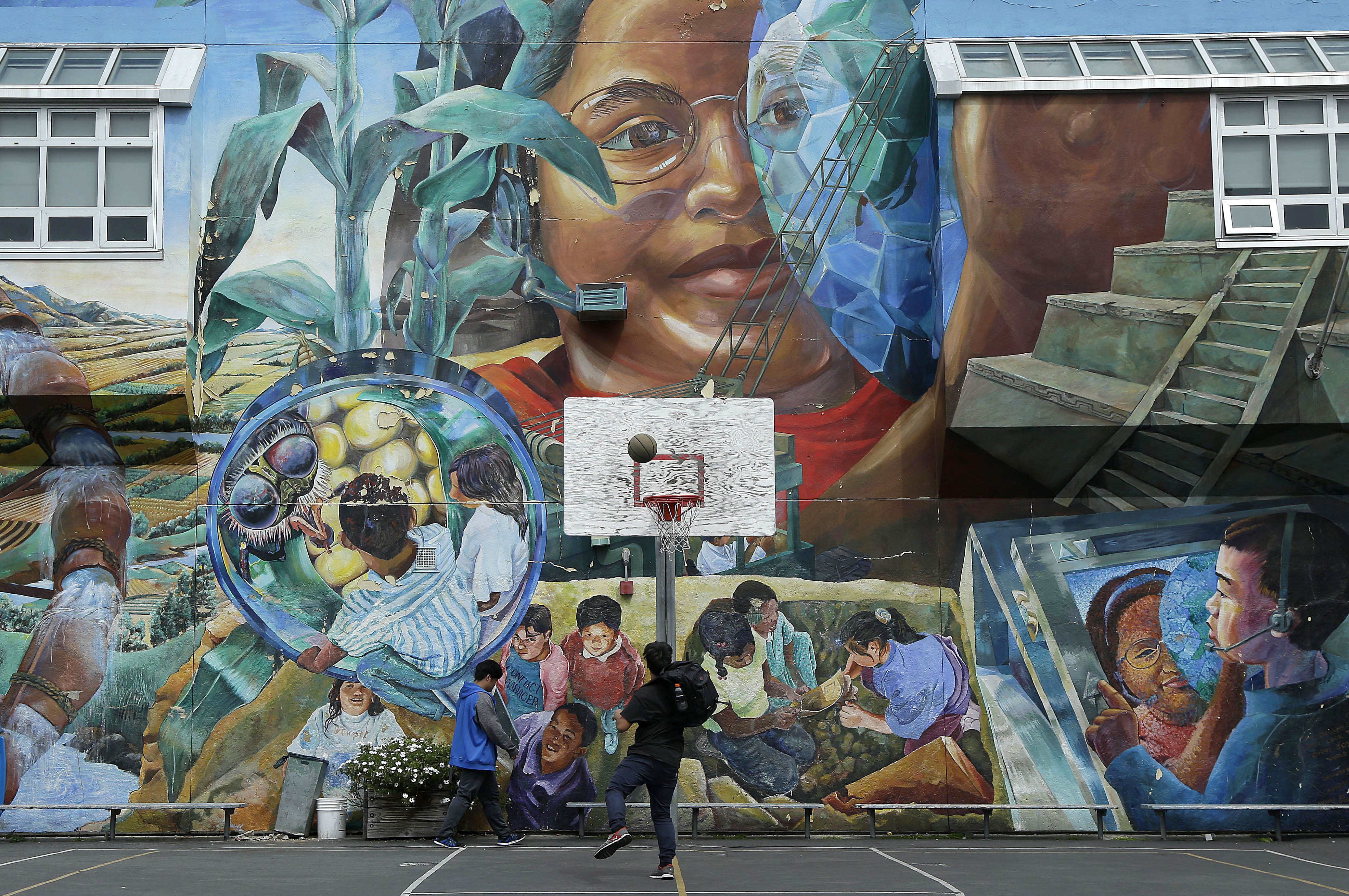 In this April 19, 2016, photo, San Francisco International High School students play basketball in the school yard after classes ended, in San Francisco. America's schools remain one of the few government institutions where migrant youth are guaranteed services, but the federal government has extended little money or oversight to monitor their impact and well-being, in part because schools are locally governed. While some districts in numerous states have discouraged migrant minors from Central America from enrolling in their schools, San Francisco International High School accommodated its youths by rewriting young-adult novels at a basic level to spark the newcomers' interest in reading. (AP Photo/Jeff Chiu)