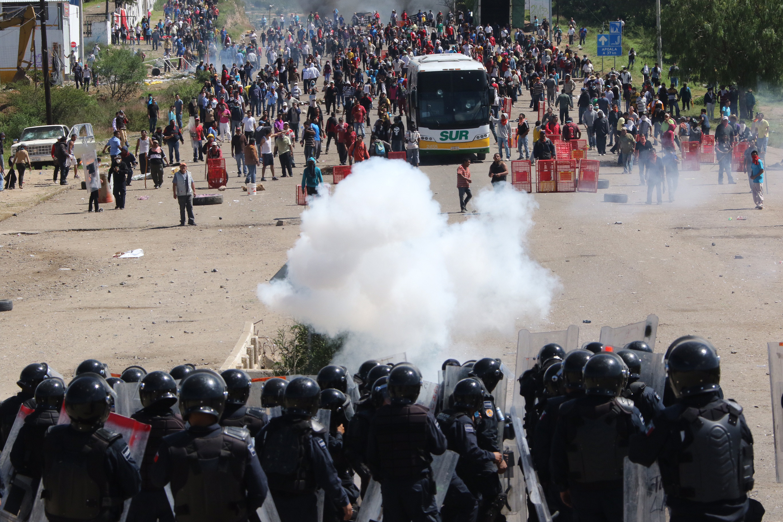 Riot police battle with protesting teachers who were blocking a federal highway in the state of Oaxaca, near the town of Nochixtlan, Mexico, Sunday, June 19, 2016. The teachers are protesting against plans to overhaul the country's education system which include federally mandated teacher evaluations.(AP Photo/Luis Alberto Cruz Hernandez)