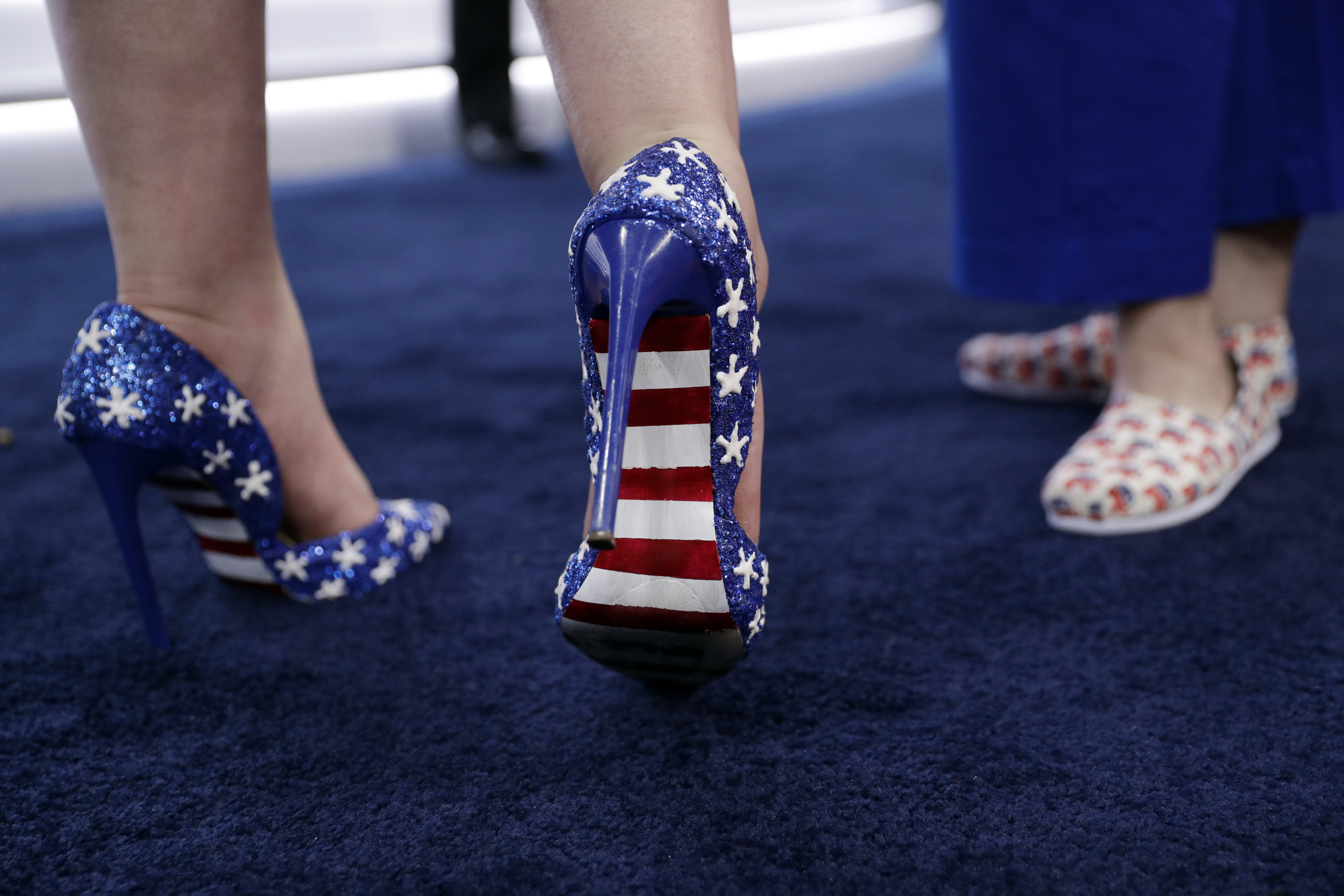 California delegate Felicia Tweedy, left, shows off her shoes during first day of the Republican National Convention in Cleveland, Monday, July 18, 2016. (AP Photo/John Locher)