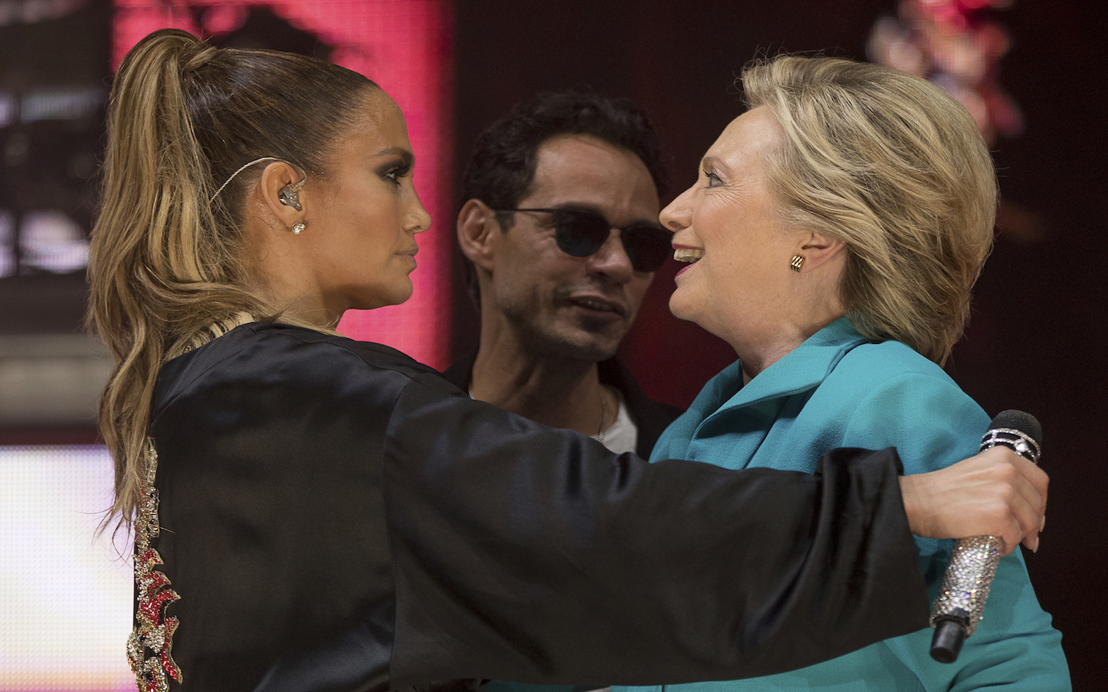 Democratic presidential candidate Hillary Clinton, right, accompanied by singer-songwriter Marc Anthony, center, hugs performer Jennifer Lopez, left, at a Get Out The Vote performance at Bayfront Park Amphitheater in Miami, Saturday, Oct. 29, 2016. (AP Photo/Andrew Harnik)
